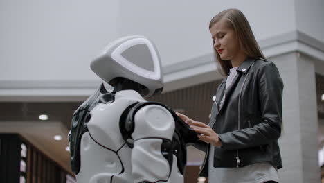 Happy-woman-in-contact-with-cyborg-robot.-Click-on-the-robot-screen.-A-droid-interacts-with-a-woman